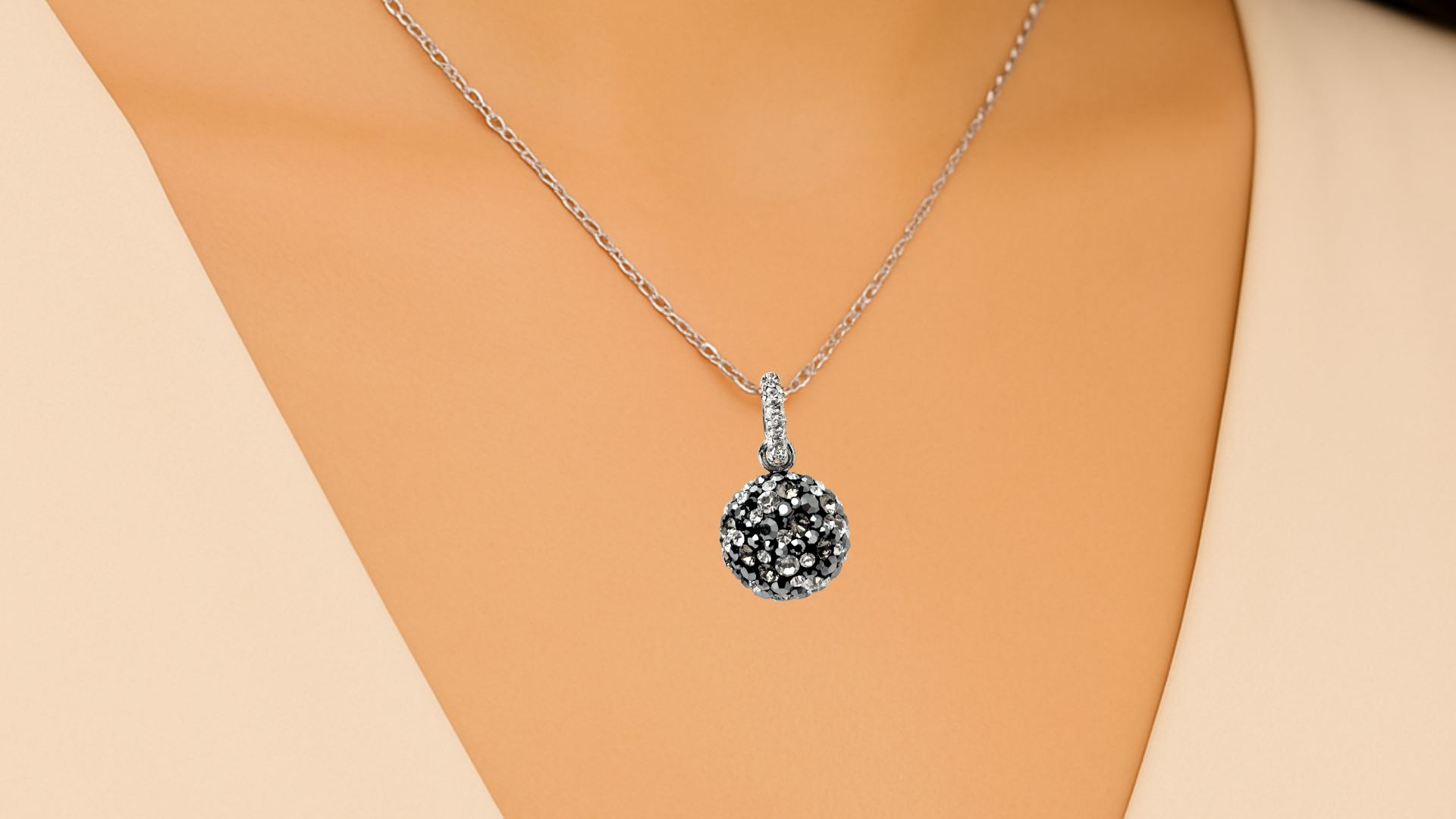 Close-up of a delicate neckline adorned with an elegant dome pendant sparkling with crystals from Europe. The wearer’s skin and collarbone are softly visible, highlighting a graceful, radiant look.