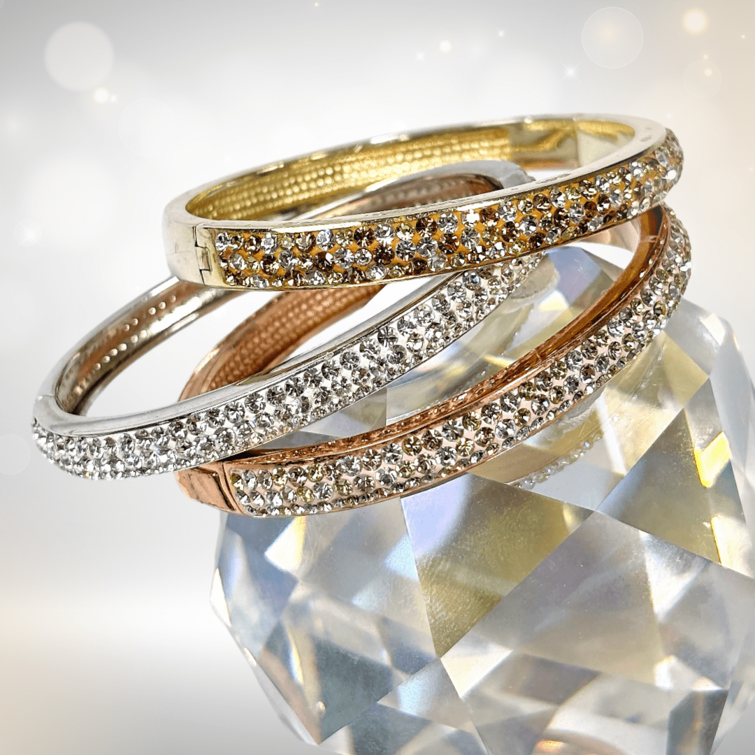 Crystal bangles and bracelets placed above a shiny disco ball with a soft sparkling background, reflecting light for a glamorous look