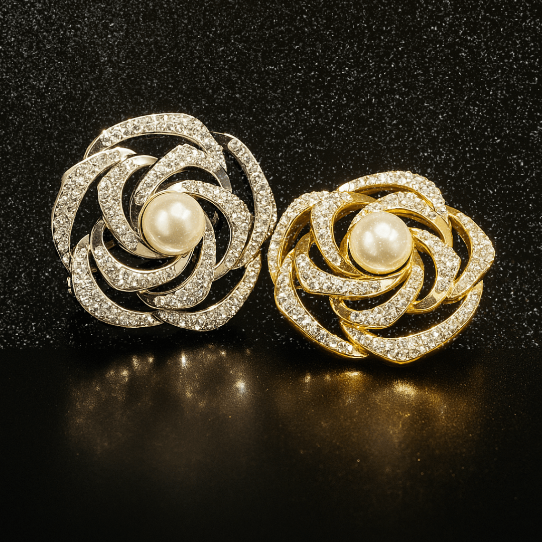 A pair of silver and gold crystal brooches displayed on a black background with a soft reflection, highlighting their sparkle and elegance